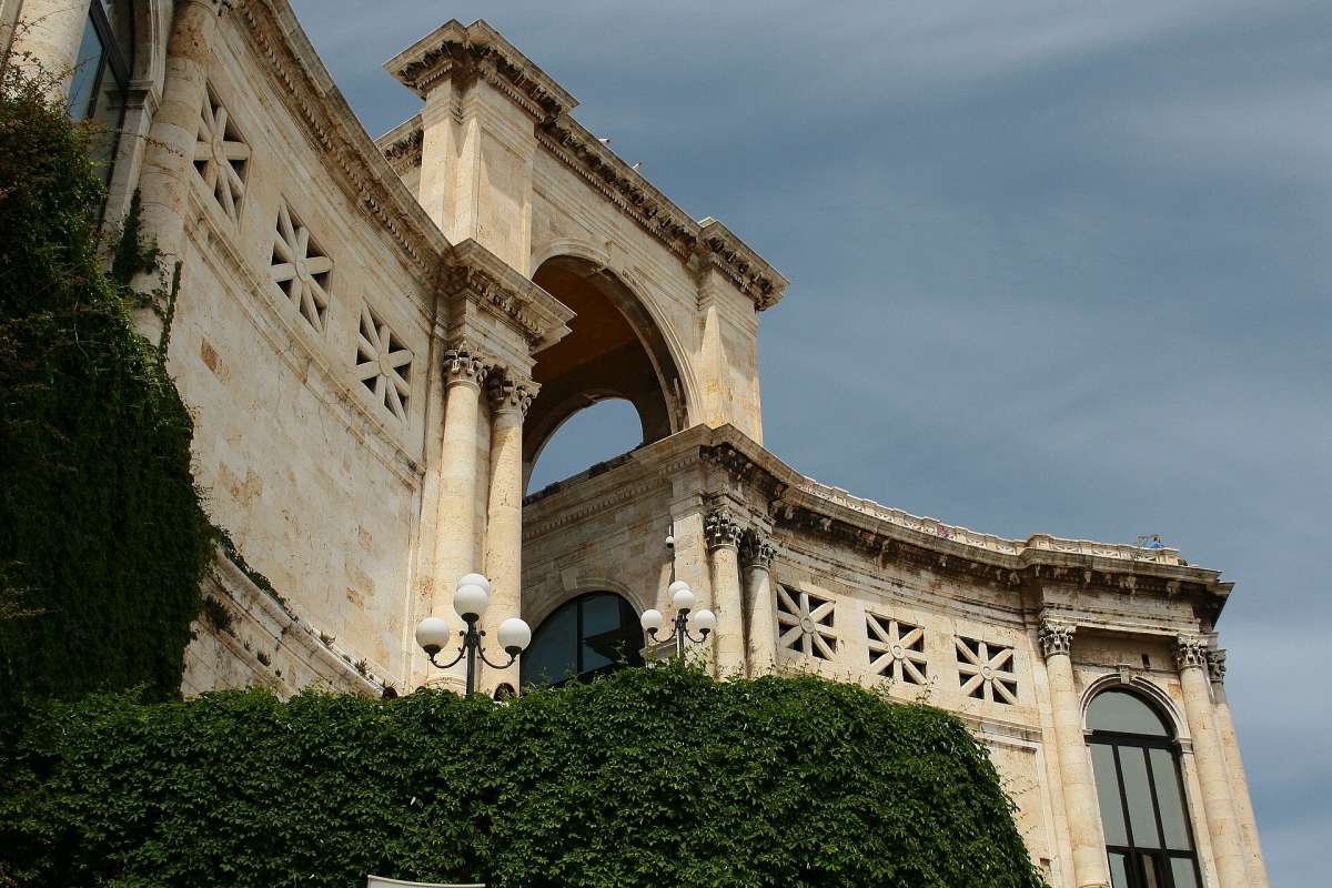 The arched limestone Bastione di Saint Remy terrace in Cagliari's old town under a cloudy sky