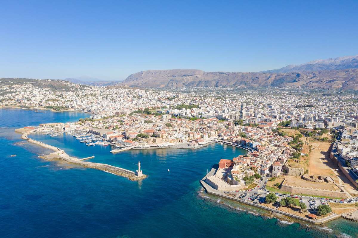 Aerial view of Chania's Venetian harbour and lighthouse, with the town and mountains behind