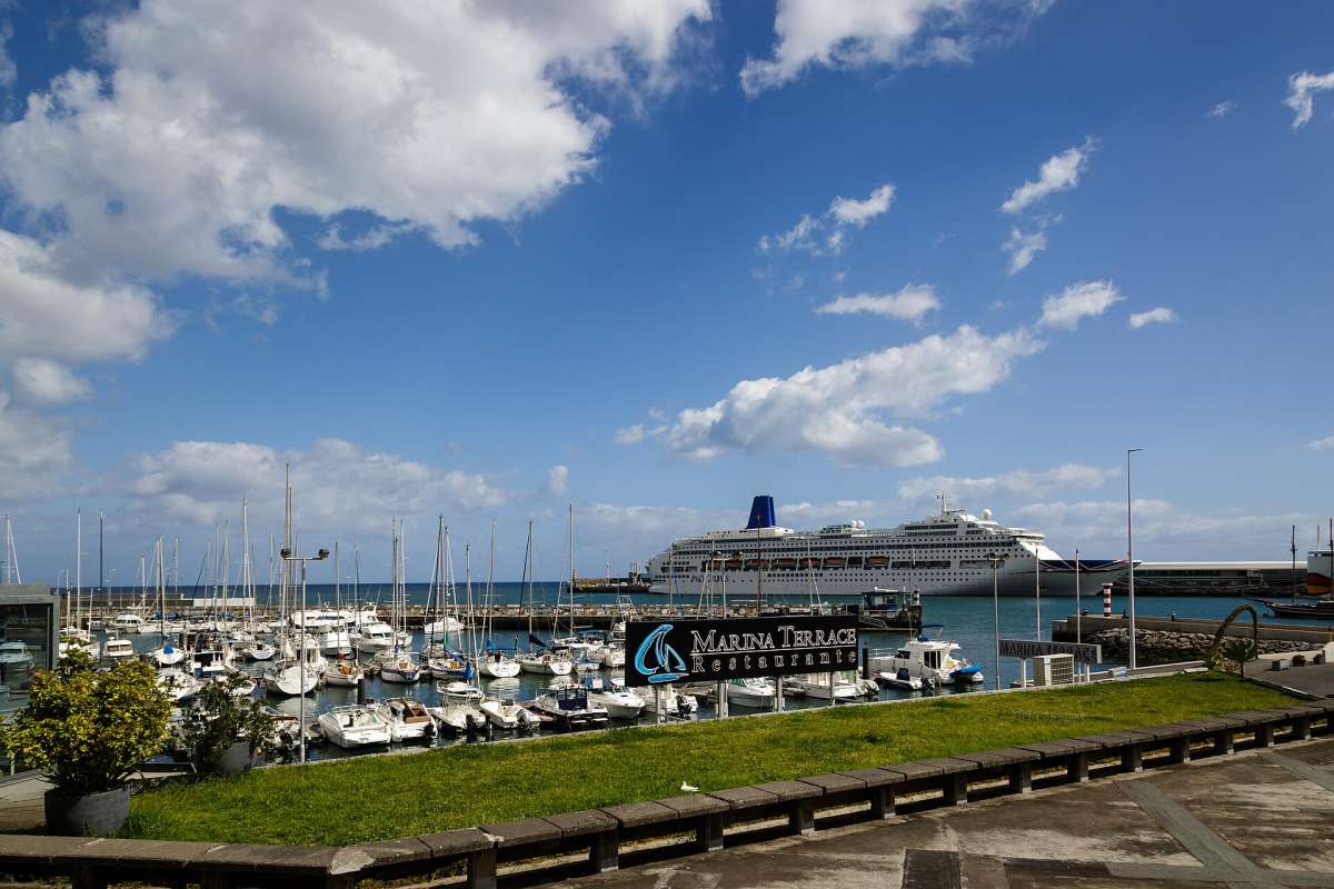 Sailboats in Funchal marina with a cruise ship in the harbour under a blue sky with clouds