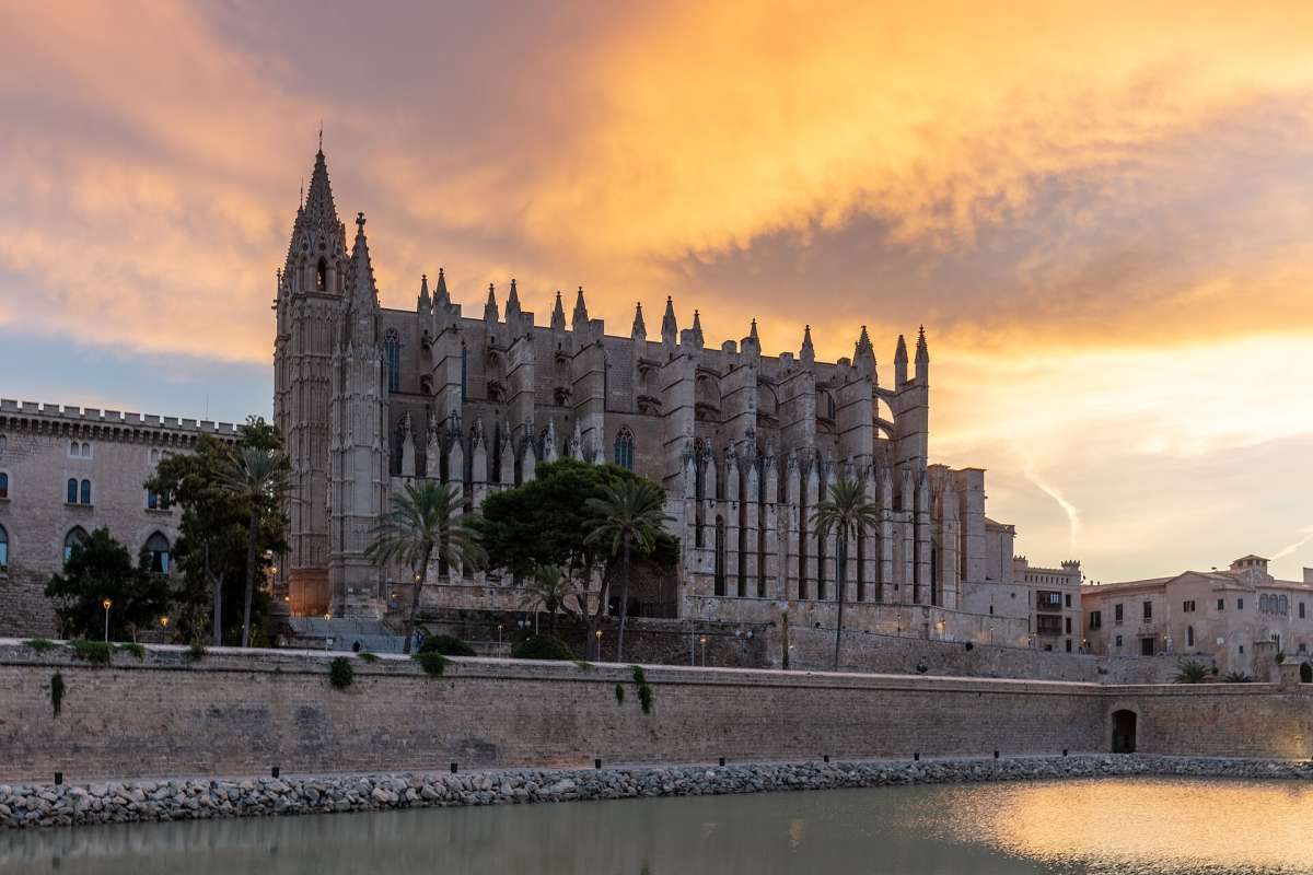 Palma's Gothic cathedral, La Seu, above the old sea wall and Parc de la Mar lake at sunset
