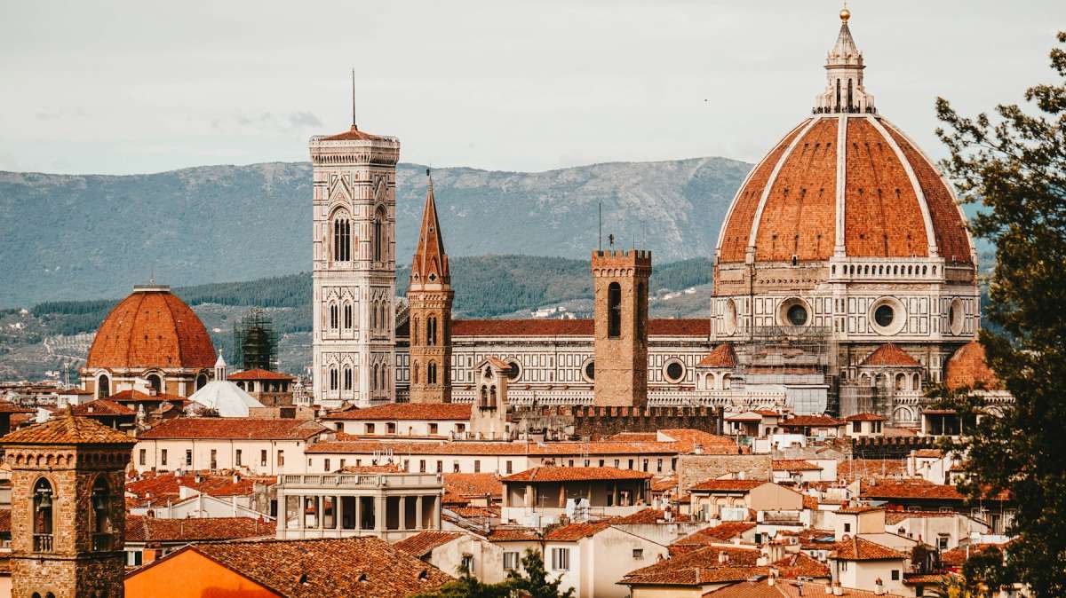 Florence Cathedral dome and Giotto's bell tower above terracotta rooftops with Tuscan hills behind