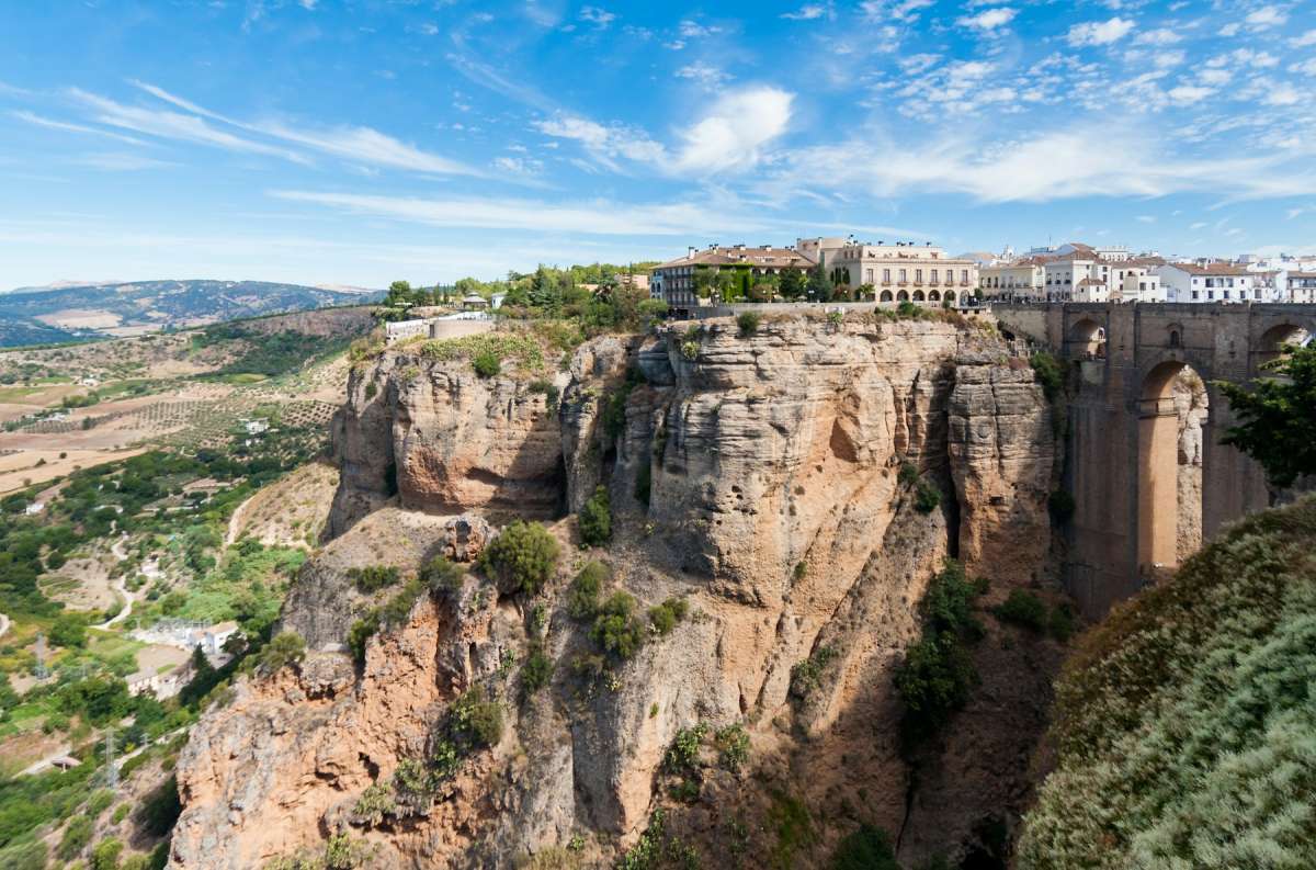 White town of Ronda perched on a sheer rocky gorge beneath a blue Andalusian sky